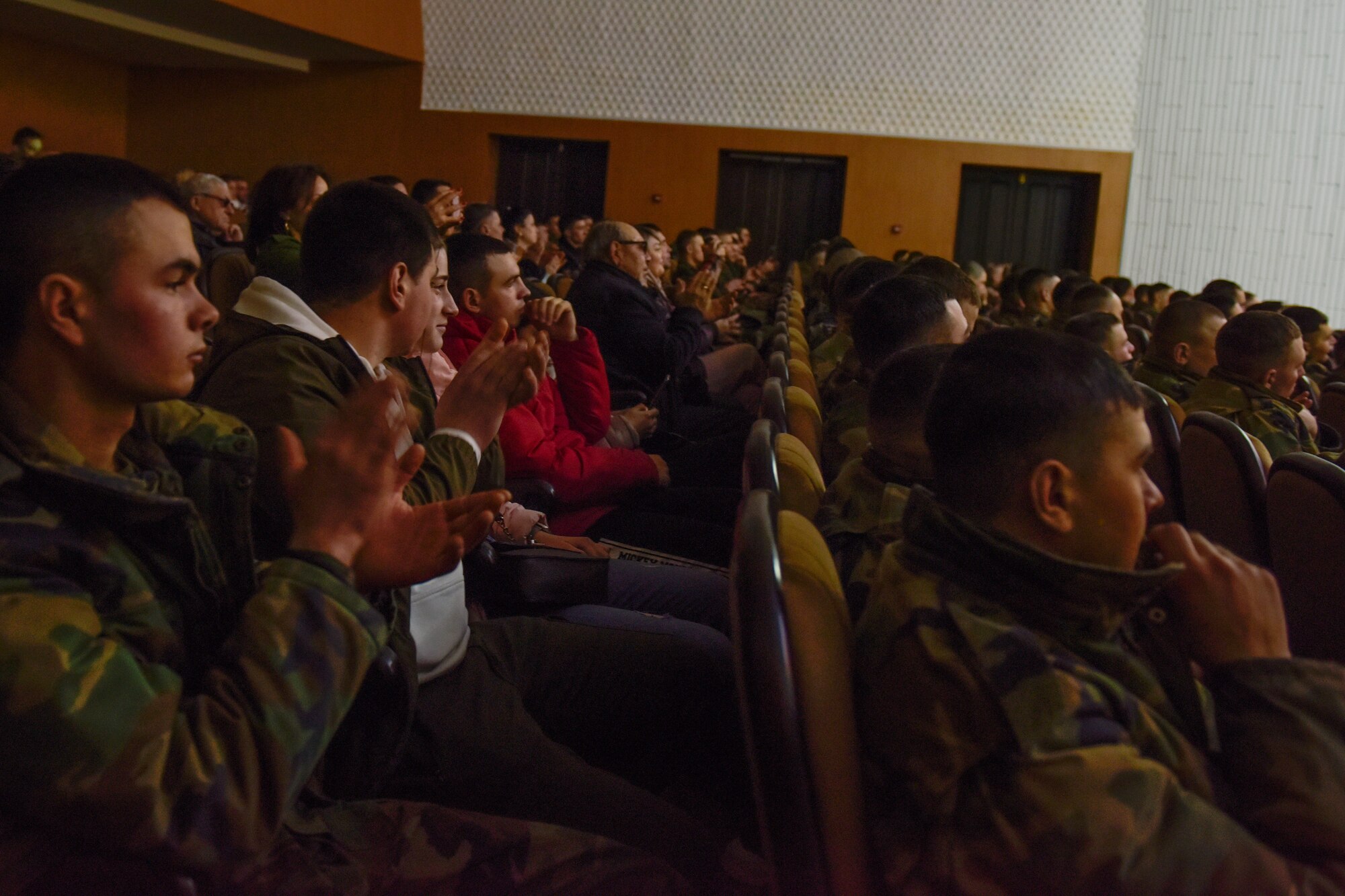 People sit in an audience and clap their hands