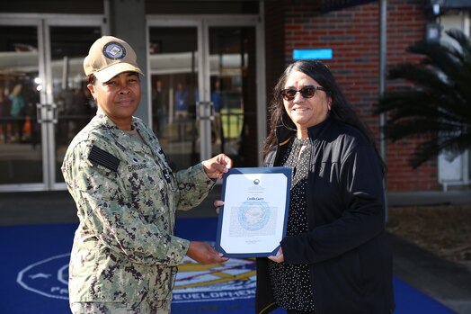  230314-N-YR423-5840 PENSACOLA, Fla. (March 14, 2023) - Naval Education and Training Professional Development Center (NETPDC) Commanding Officer Capt. Willie Brisbane presents Cecelia Castro with the junior Civilian of the Year (COY) award for 2022. Castro's selection was based on her superior performance in fleet support and outstanding customer service as she ensured Navy Enlisted Advancement System (NEAS) readiness during a dynamic period of consolidation. (U.S. Navy photo by Cheryl Dengler)