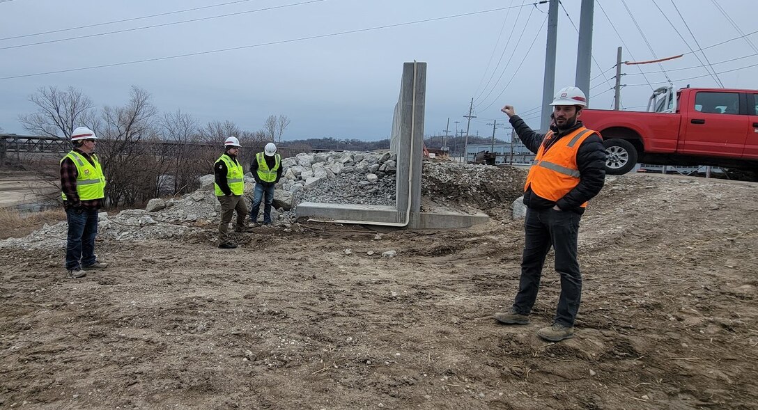 People in reflective vests and hard hats stand outside on a construction site.