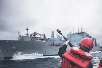 Gunner's Mate 3rd Class Camron Bruns fires a shot-line from USS McFaul (DDG 74) to USNS William McLean (T-AKE 12).