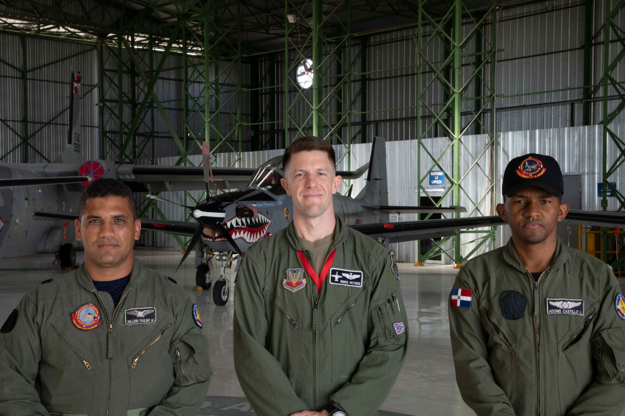 Two Fuerza Aérea de República Dominicana members and U.S. Air Force Maj. Zachary Peters, 75th Expeditionary Fighter Squadron weapons and tactics chief, middle, stand in front of FARD aircraft at San Isidro Air Base, Dominican Republic, Feb. 16, 2023. Exercise Forward Tiger was designed to build on longstanding partnerships throughout the Caribbean and contribute to enhanced military readiness, humanitarian relief, and disaster response capabilities. (U.S. Air Force photo by 1st Lt. Christian Little)