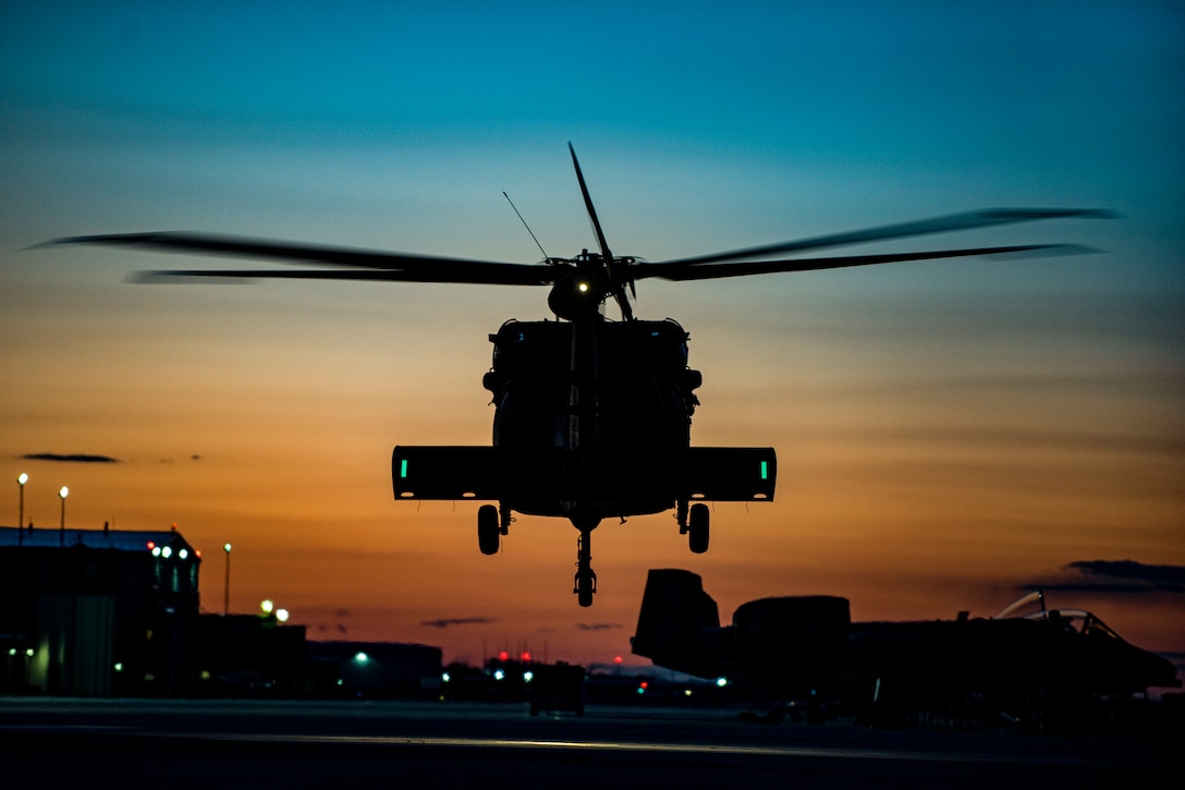 A helicopter flies as the sun sets.