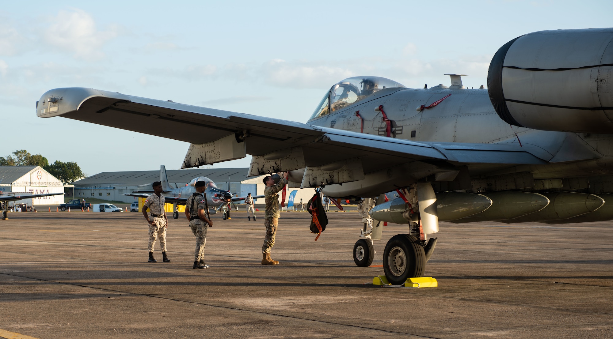 Members of the Dominican Republic Air Force (FARD) watch as a U.S. Airman from the 23rd Air Expeditionary Wing ensures an A-10C Thunderbolt II is prepared as a static display for an airshow at San Isidro Air Base, Dominican Republic, Feb. 19, 2023. The airshow was dedicated to the FARD's 75th anniversary where both U.S. and Dominican Republic aircraft demonstrated capabilities and strengthened their bond as partner nations.(U.S. Air Force photo by Tech. Sgt. Jessica H. Smith-McMahan)