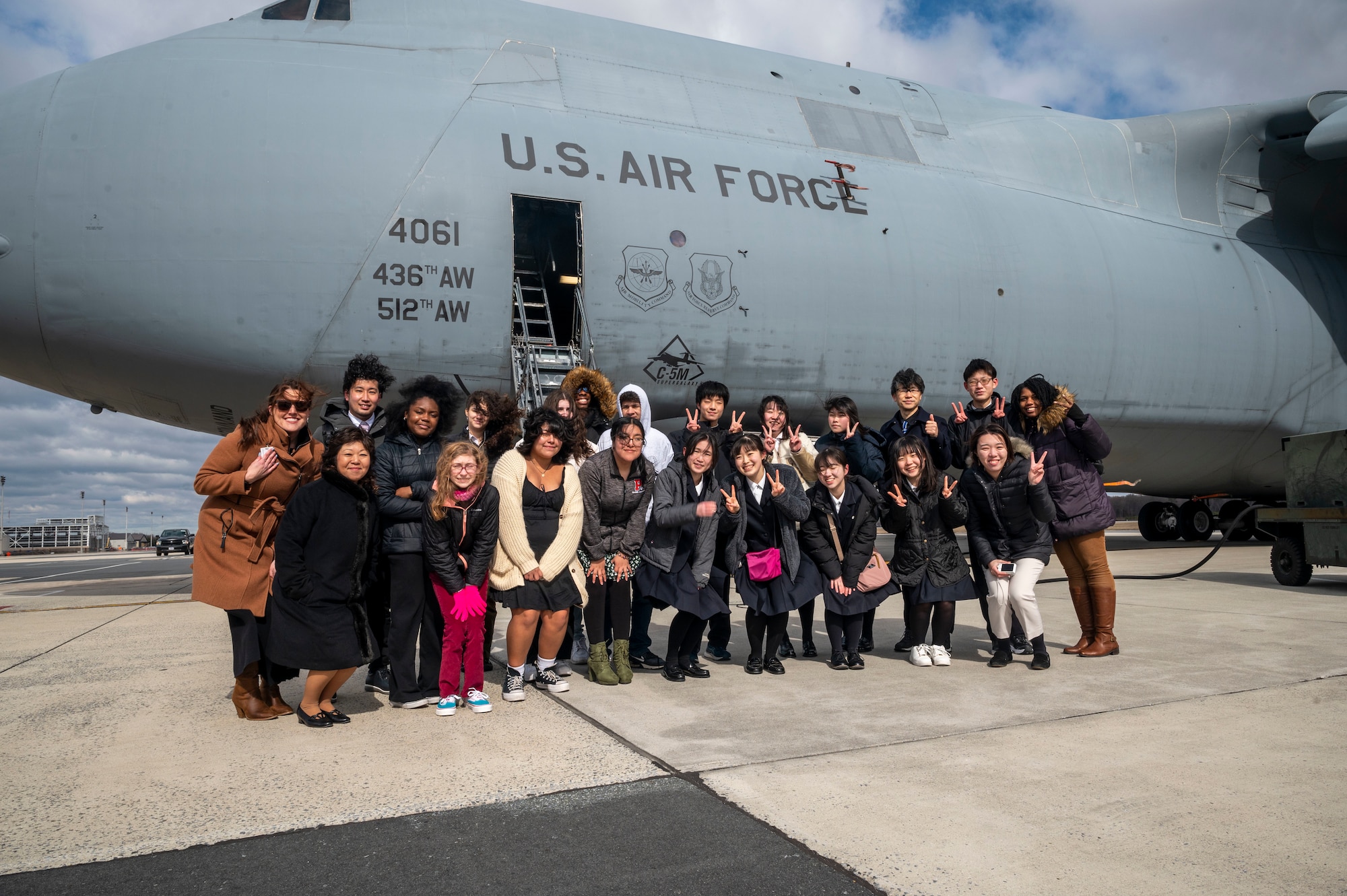 A tour group including Japanese students from Sendai, Miyagi, Japan, and local students from POLYTECH High School, pose for a photo outside a C-5M Super Galaxy during a visit to Dover Air Force Base, Delaware, March 14, 2023. Since 2000, the state of Delaware and Dover AFB have maintained a strong partnership with the prefecture of Miyagi delegates. Delaware and Miyagi are sister states that foster business, education and cultural exchanges. (U.S. Air Force photo by Staff Sgt. Marco A. Gomez)