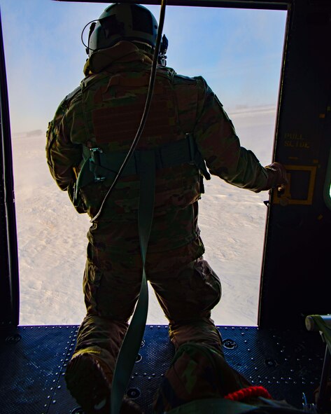 Senior Airman Garrett Hightower (left), 54th Helicopter Squadron (HS) flight engineer, lowers Airman 1st Class Caulder Taylor (bottom center), 54th HS special missions aviator, to the ground with a rescue hoist from a UH-1N Huey in rural North Dakota, March 13, 2023. 54th HS helicopters typically fly from ground level to 2,000 feet above ground level. Operations may require flight up to 15,000 feet above mean sea level. (U.S. Air Force photo by Staff Sgt. Michael A. Richmond)