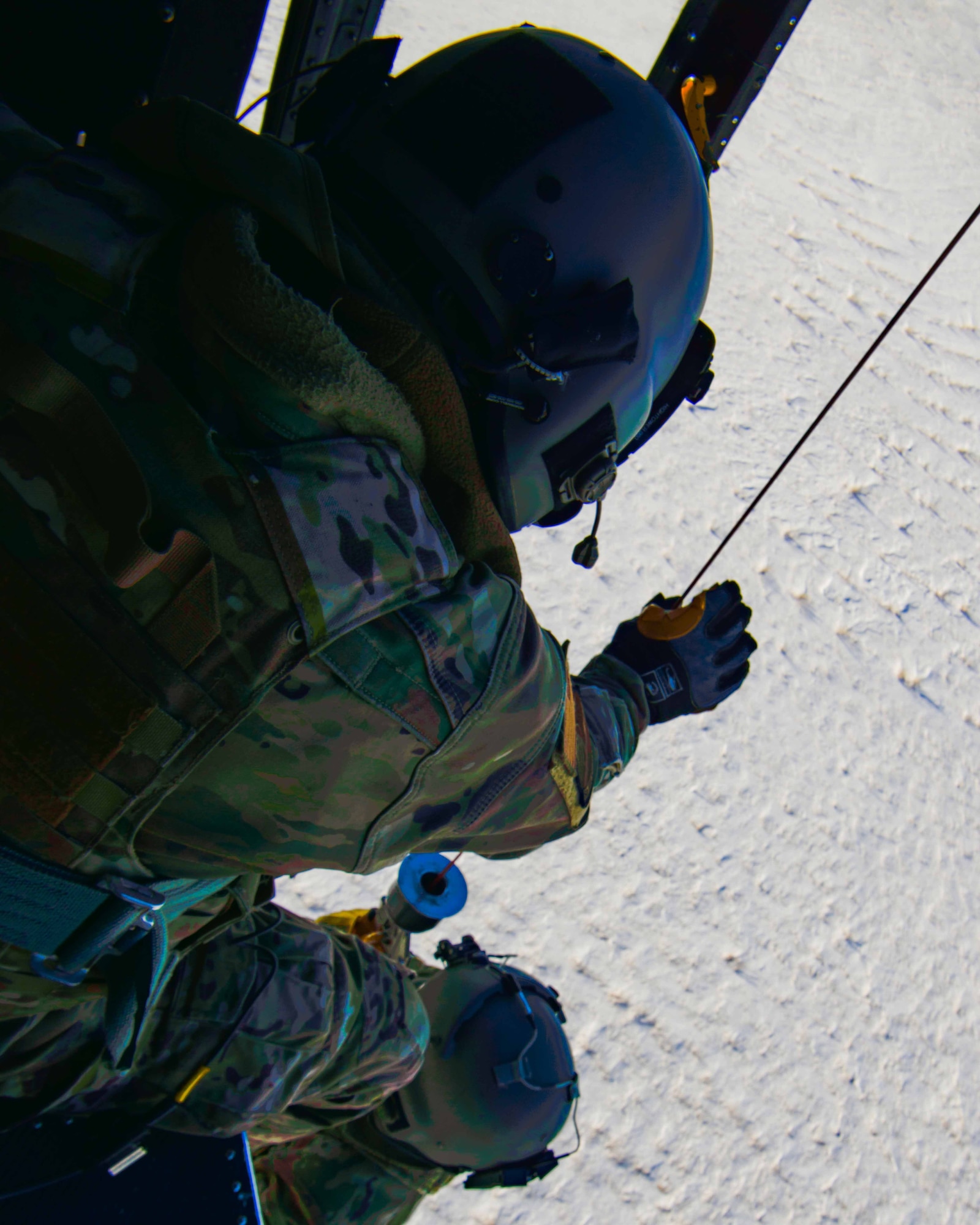 Senior Airman Garrett Hightower (left), 54th Helicopter Squadron (HS) flight engineer, lowers Airman 1st Class Caulder Taylor (bottom center), 54th HS special missions aviator, to the ground with a rescue hoist from a UH-1N Huey in rural North Dakota, March 13, 2023. 54th HS helicopters typically fly from ground level to 2,000 feet above ground level. Operations may require flight up to 15,000 feet above mean sea level. (U.S. Air Force photo by Staff Sgt. Michael A. Richmond)