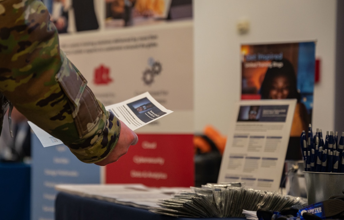 A Team Dover Airman grabs a flyer from the United Training booth during the 2023 Dover Air Force Base Tech Expo at Dover AFB, Delaware, March 15, 2023. The event provided Airmen the opportunity to meet face to face with more than 20 leading tech companies. (U.S. Air Force photo by Senior Airman Cydney Lee)