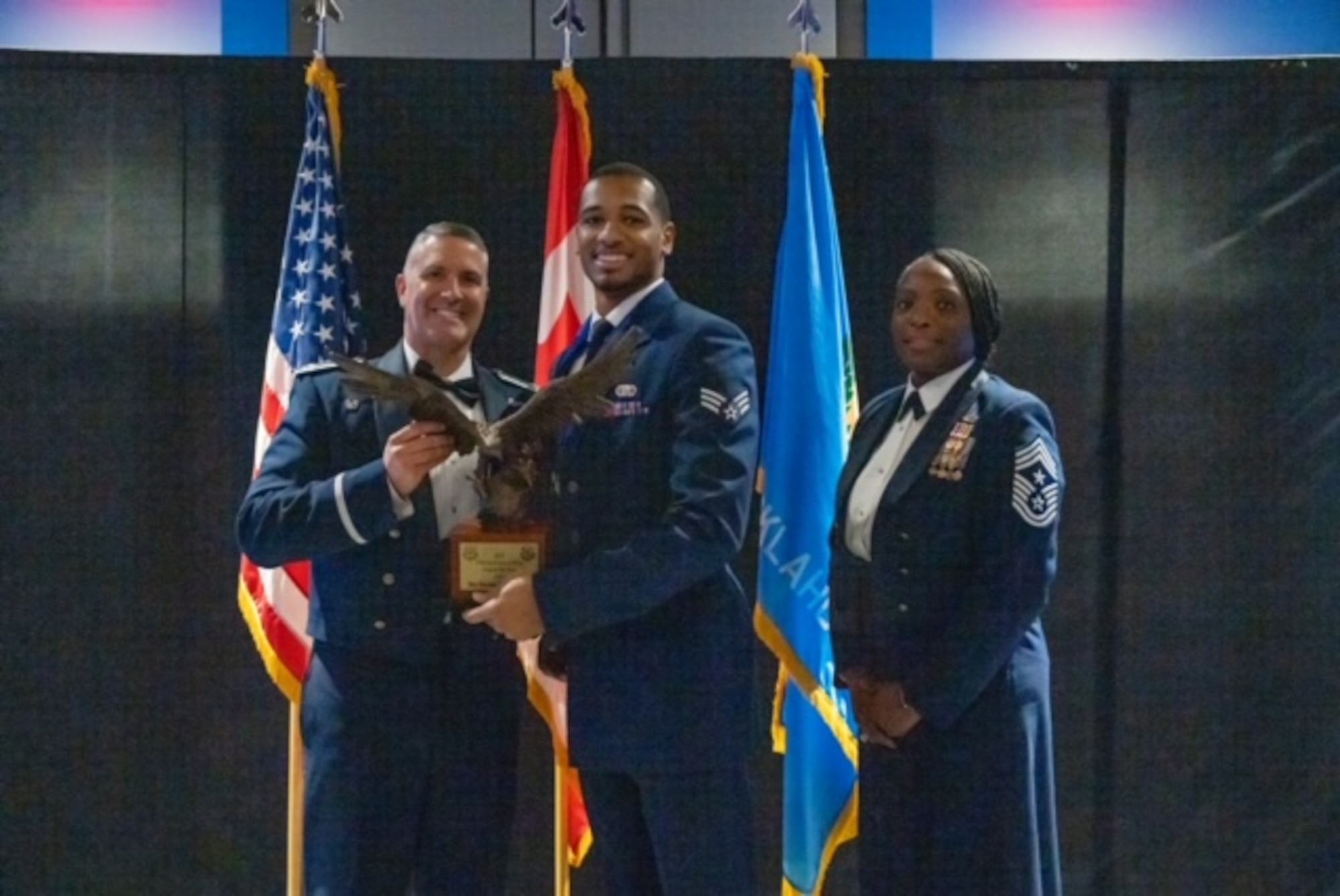 Three people posing for group with award.