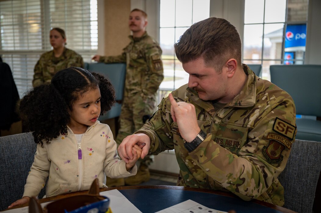 Male defender shows young child how to finger print.