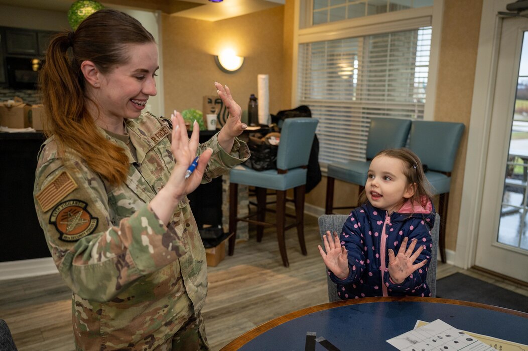 Female defender engages with young child during a finger print demonstration.