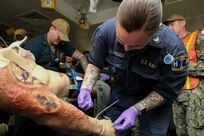 SAN DIEGO (March 8, 2023) – Hospital Corpsman 3rd Class Amanda Eldridge inserts an IV into the arm of a simulated trauma patient during a mass casualty drill aboard USS Boxer (LHD 4). Boxer, Fleet Surgical Team Five and Navy Medicine Readiness and Training Command San Diego Sailors participated in a two-day mass casualty drill simulating Boxer as a casualty receiving treatment ship. Boxer is a Wasp-class amphibious assault ship homeported in San Diego. (U.S. Navy photo by Mass Communication Specialist 1st Class Kelsey J. Hockenberger)