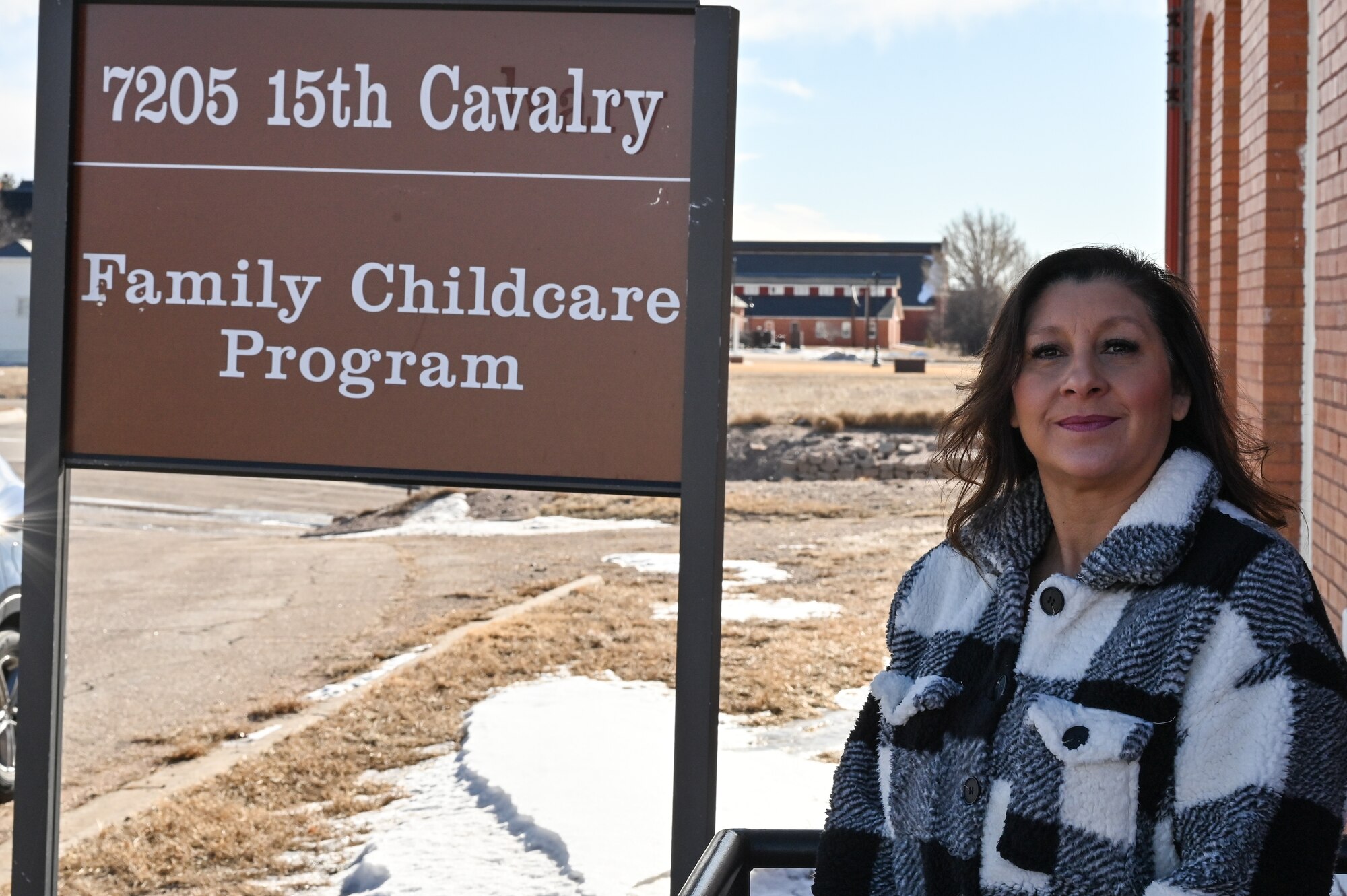 Joyce Cisneros, 90th Force Support Squadron community childcare coordinator, poses in front of the FCC program sign on F. E. Warren Air Force Base, Wyoming, Feb. 28, 2023. Cisneros is looking for FCC providers to join the Wrangler family. For those interested in becoming an FCC provider or learning more about the program, they can contact her at 307-773-3317. (U.S. Air Force photo by Joseph Coslett Jr.)