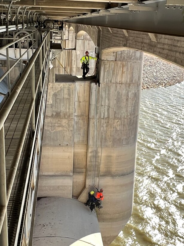 JOHN MARTIN DAM, Colo. – A contractor ropes team scales the nose pier on the upstream side of the dam, Nov. 8, 2022. Three-person ropes team installed instrumentation cables and conduit up the face of the dam from borings in the lake, assisted by a dive team. Photo by Chris Carroll. This photo tied for third place based on employee voting.