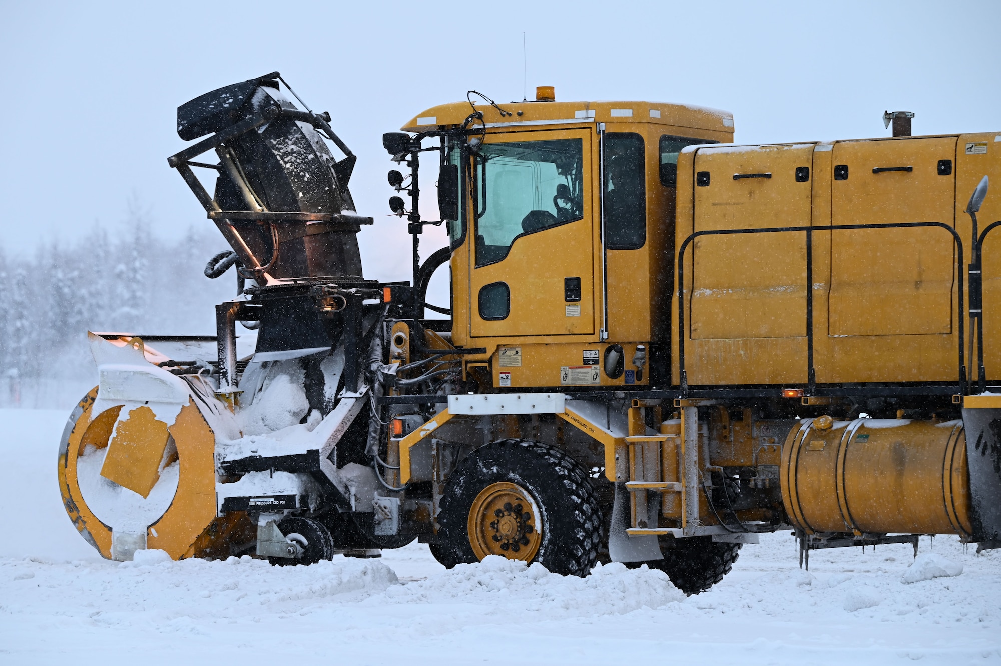 U.S. Air Force Airmen assigned to the 354th Civil Engineer Squadron wait in snow brooms on the flight line at Eielson Air Force Base, Alaska, Jan. 23, 2023.