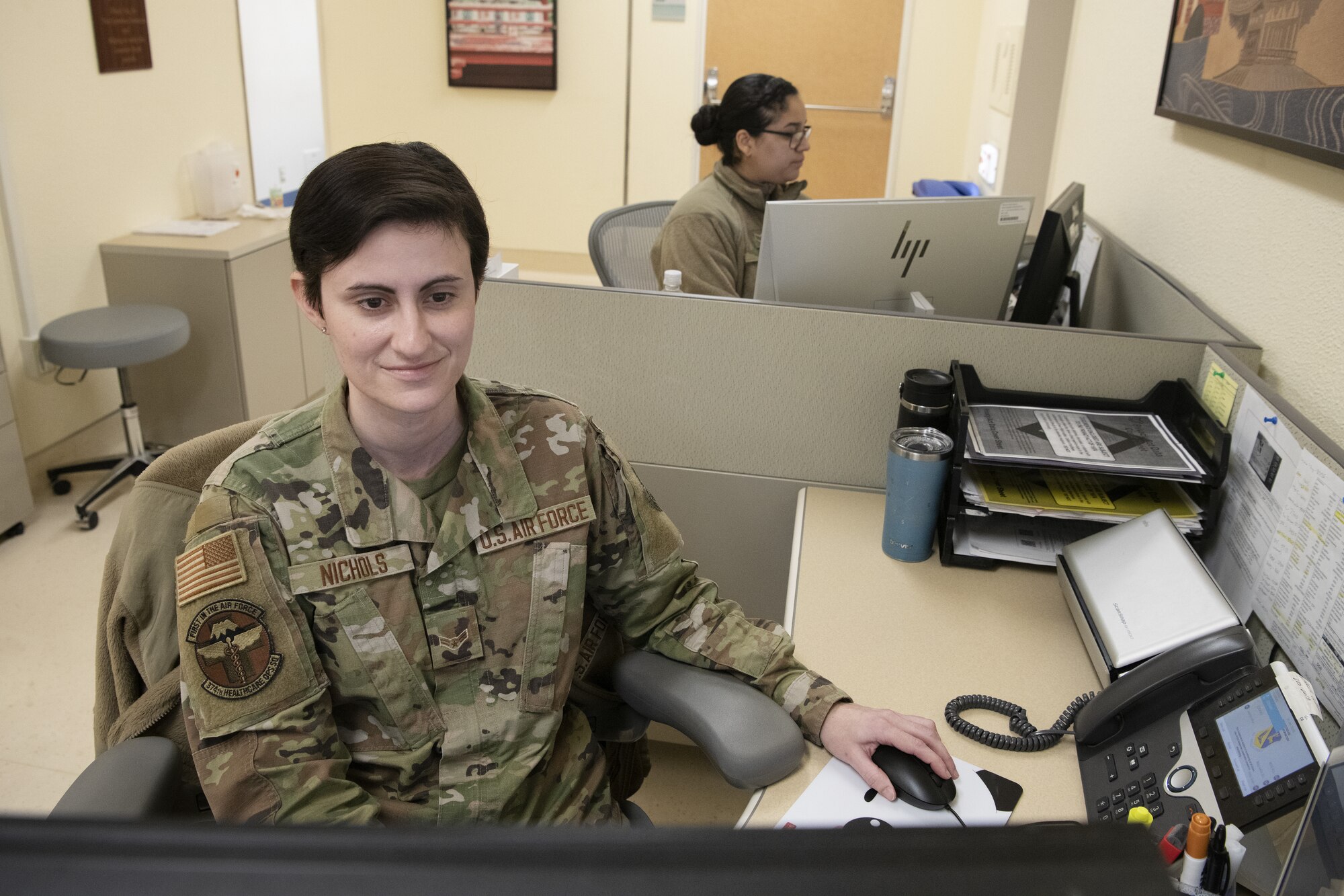 Airman 1st Class Melissa Nichols, foreground, and Staff Sgt. Monica Jaime, background,  checks in patients and schedules appointments at the Internal Medicine Clinic located at Yokota Air Base, Japan.