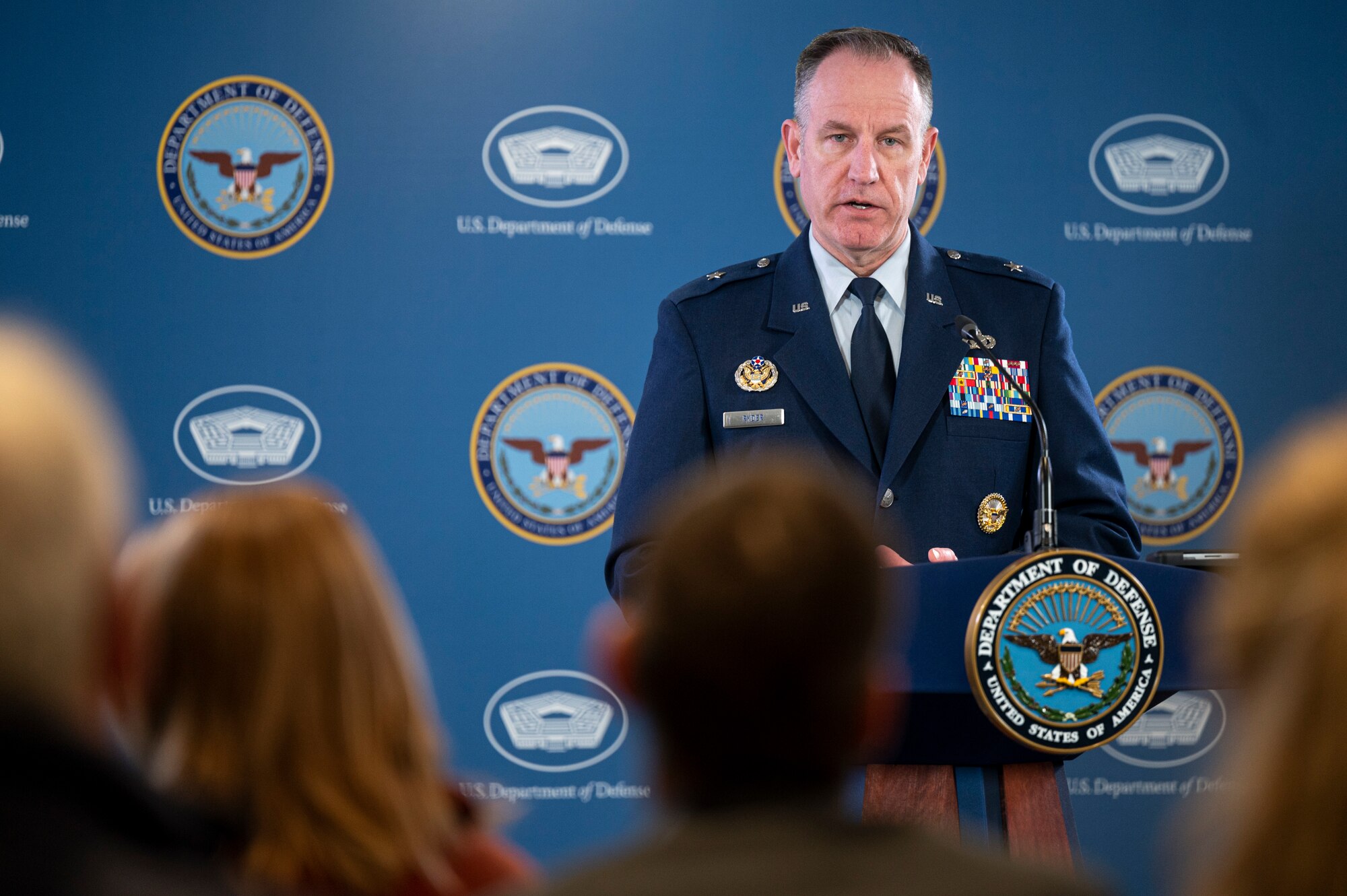 A man in a military uniform stands behind a lectern.