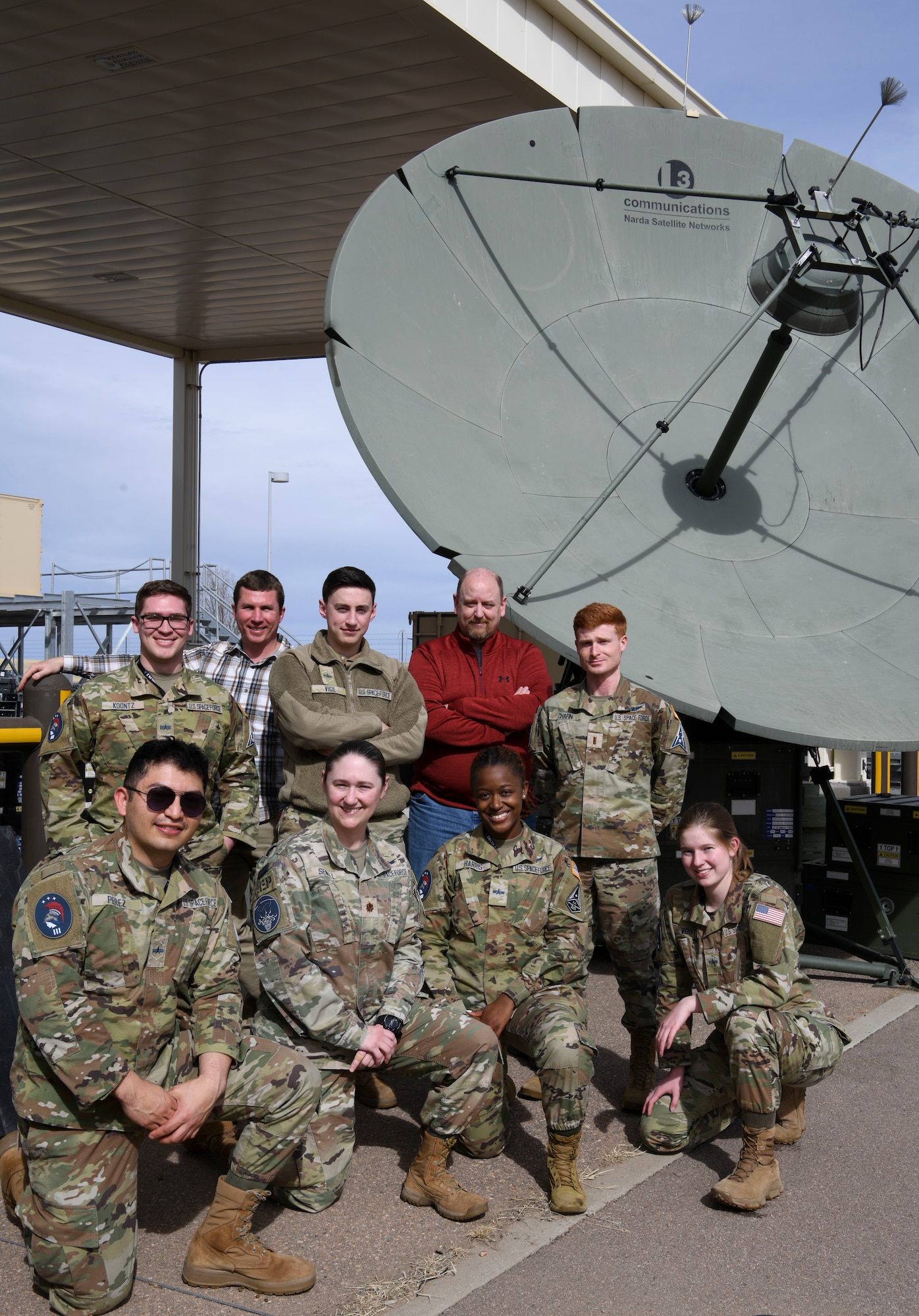 Students pose in front of satellite.