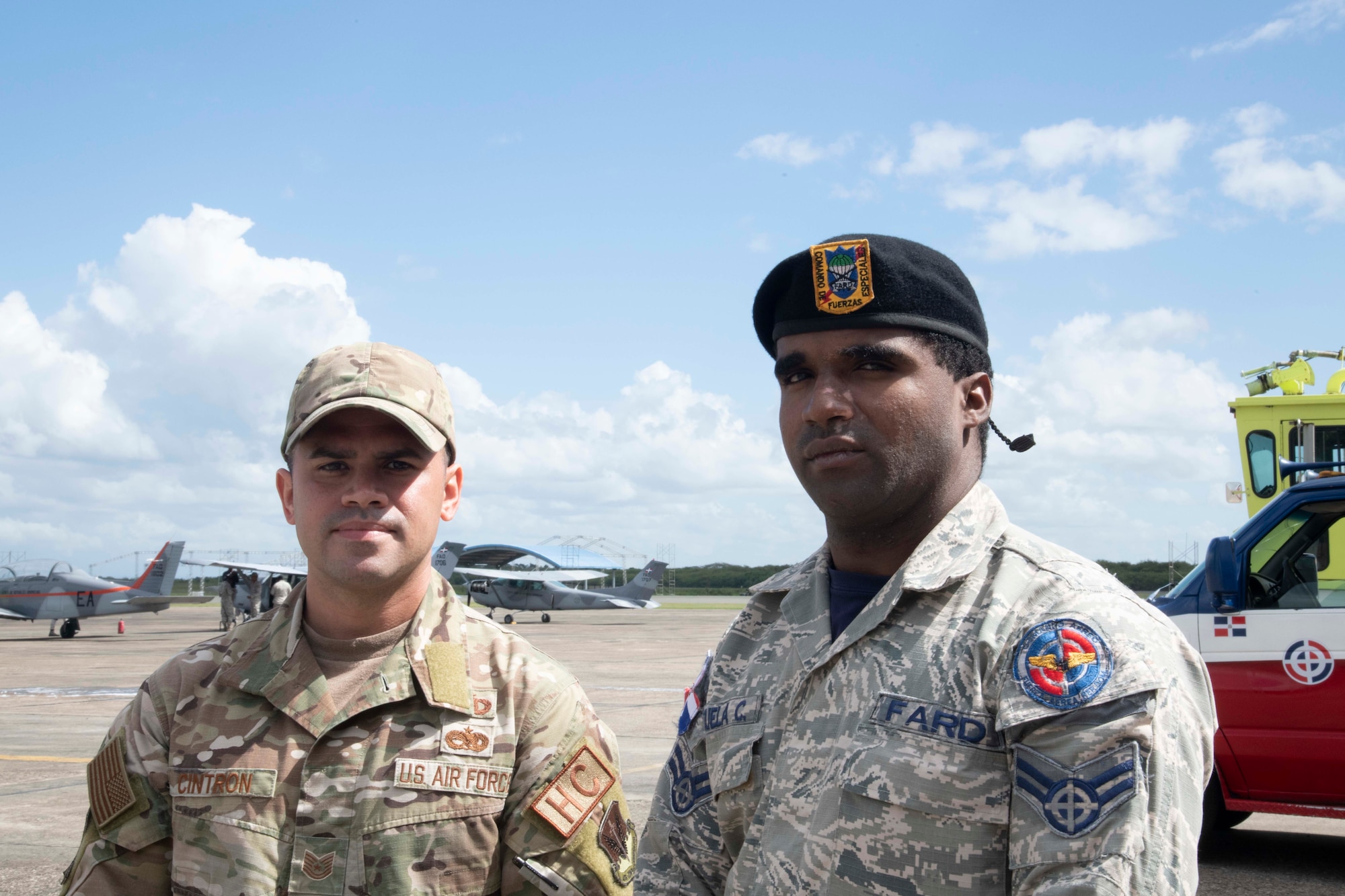 Fuerza Aérea de República Dominicana Cabo Zarzuela Cuevas, firefighter, right, and U.S. Air Force Tech. Sgt. Giancarlo Cintron, religious affairs noncommissioned officer, stand on the flight line at San Isidro Air Base, Dominican Republic, Feb. 16, 2023. These members are preparing for exercise Forward Tiger was designed to build on longstanding partnerships throughout the Caribbean and contribute to enhanced military readiness, humanitarian relief, and disaster response capabilities. (U.S. Air Force photo by 1st Lt. Christian Little)