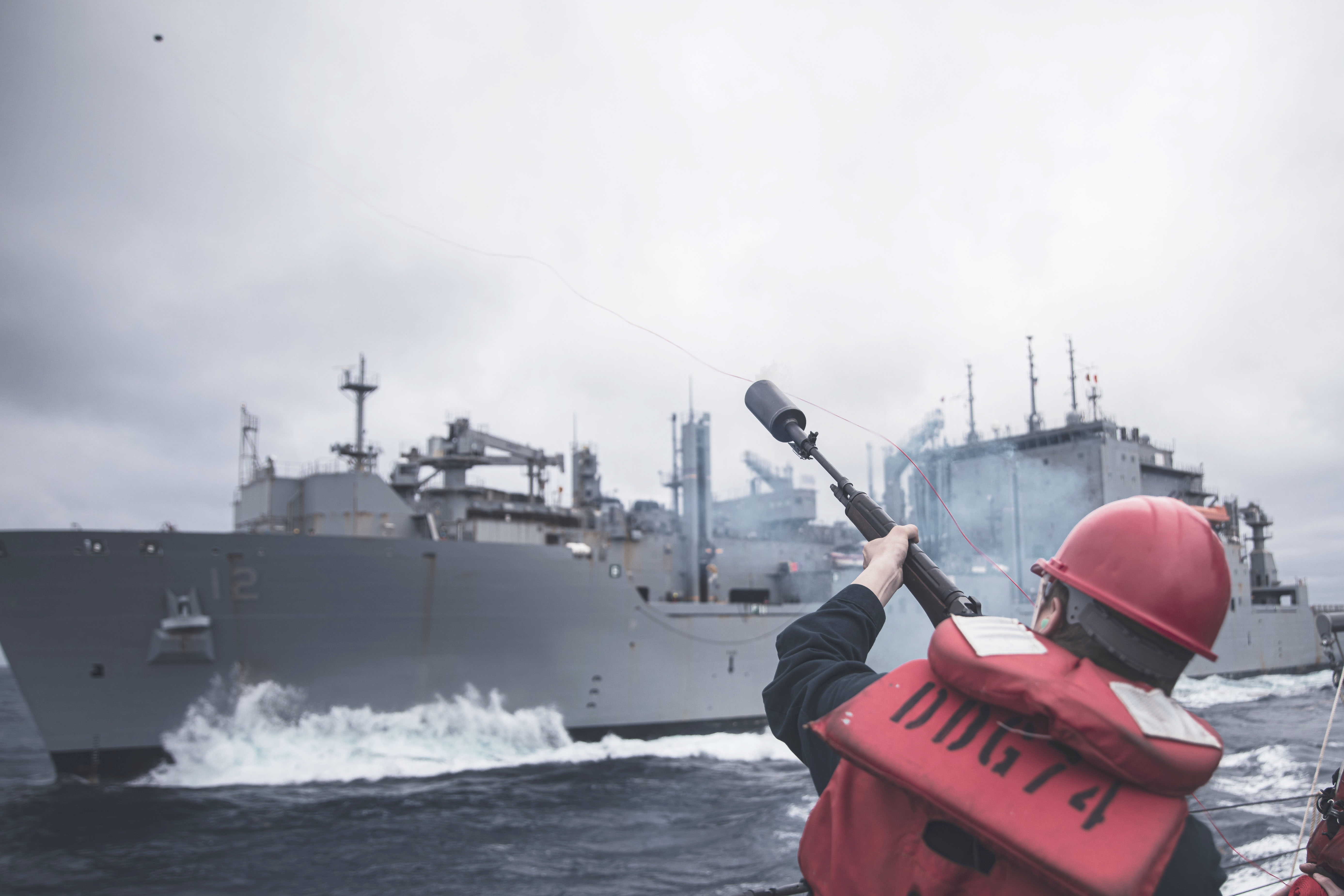Gunner's Mate 3rd Class Camron Bruns fires a shot-line from USS McFaul (DDG 74) to USNS William McLean (T-AKE 12).
