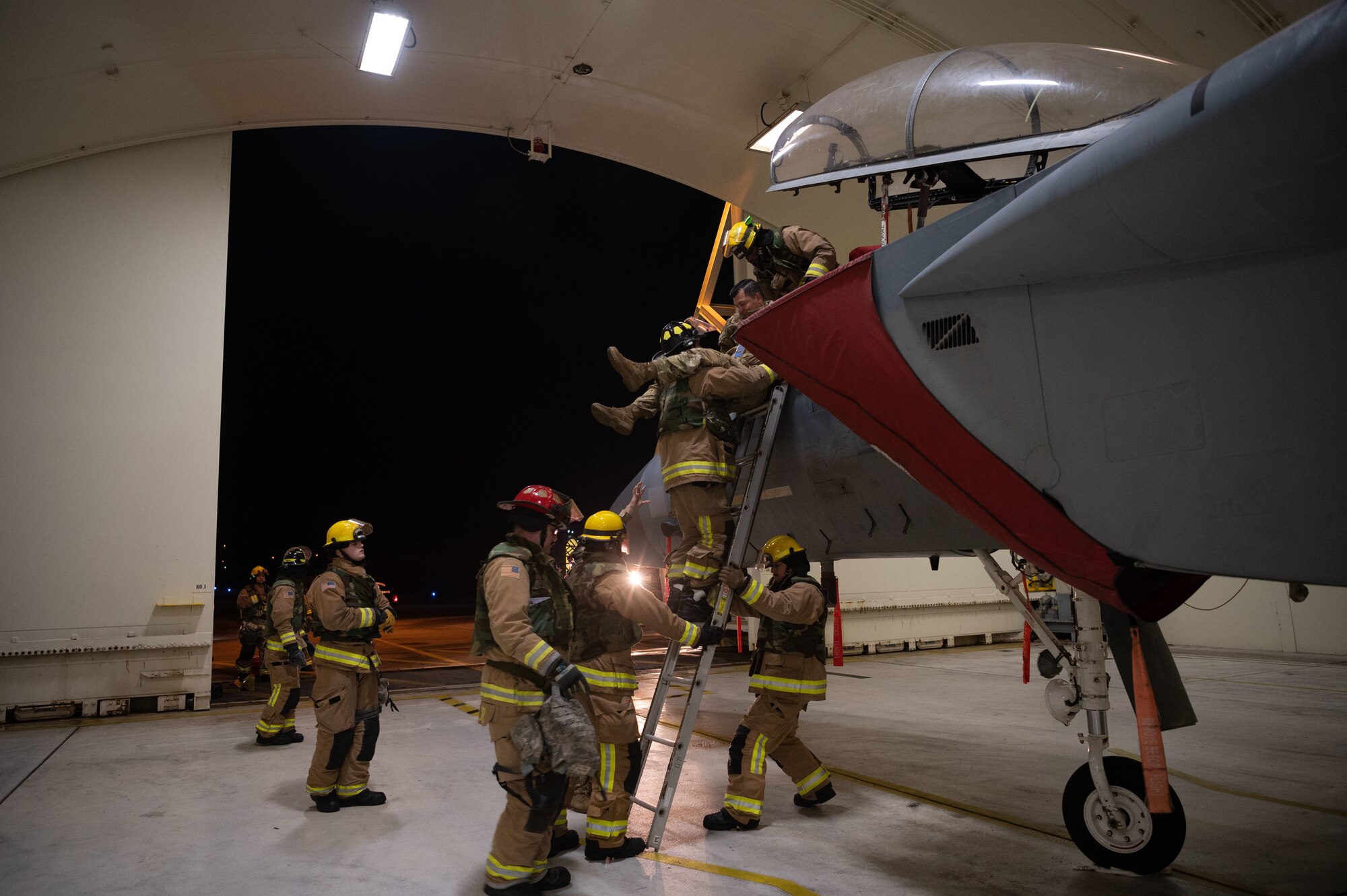 Firefighters carry Airman from aircraft