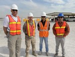 Four men pose in a deployed location