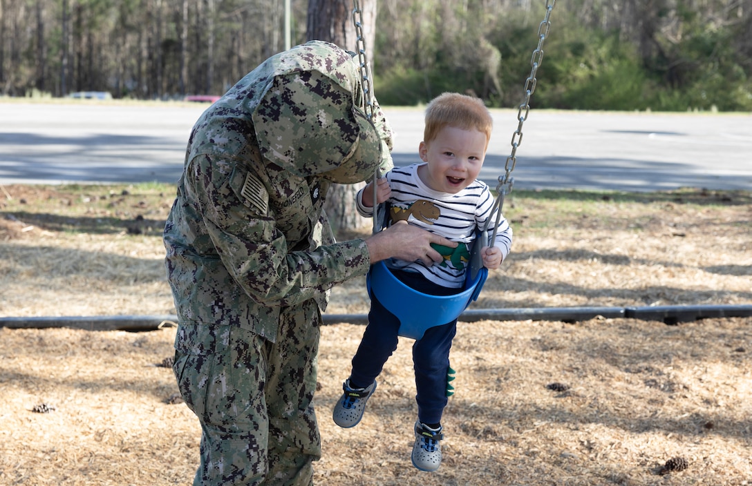 U.S. Navy Cmdr. Brian Schonefeld, Facilities director for Marine Corps Air Station (MCAS) Cherry Point, and his son, play on the new swing set after the ribbon cutting ceremony in the Nugent Cove housing community, Marine Corps Air Station Cherry Point, North Carolina, March 9, 2023. The swing set will provide closer and more suitable recreation areas for children and families within the community, making safer and easier routes to access nearby facilities in their community.  (U.S. Marine Corps photo by Lance Cpl. Tristen Reed)
