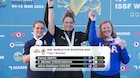 Women in their country's uniform celebrating with medals in front of ISSF World Cup banner.