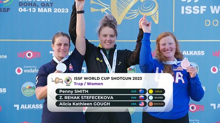 Women in their country's uniform celebrating with medals in front of ISSF World Cup banner.