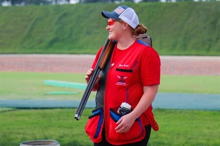 Woman in U.S.A. uniform with shotgun outdoors.