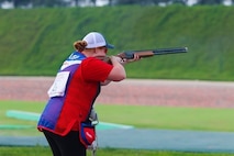 Woman in U.S.A. uniform with shotgun shoots a clay target.
