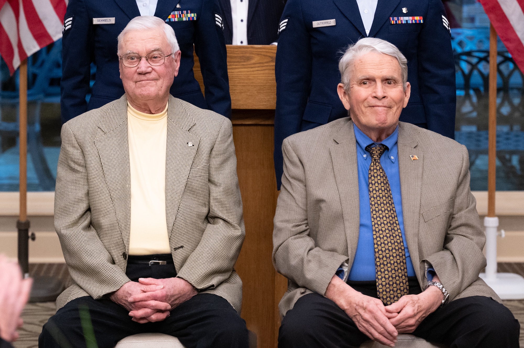 Two men sit on chairs.