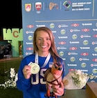 Woman in U.S.A. uniform with medal in front of ISSF backdrop.