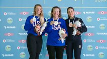 Three women in their country's uniform posing with medals in front of ISSF backdrop.