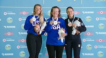 Three women in their country's uniform posing with medals in front of ISSF backdrop.