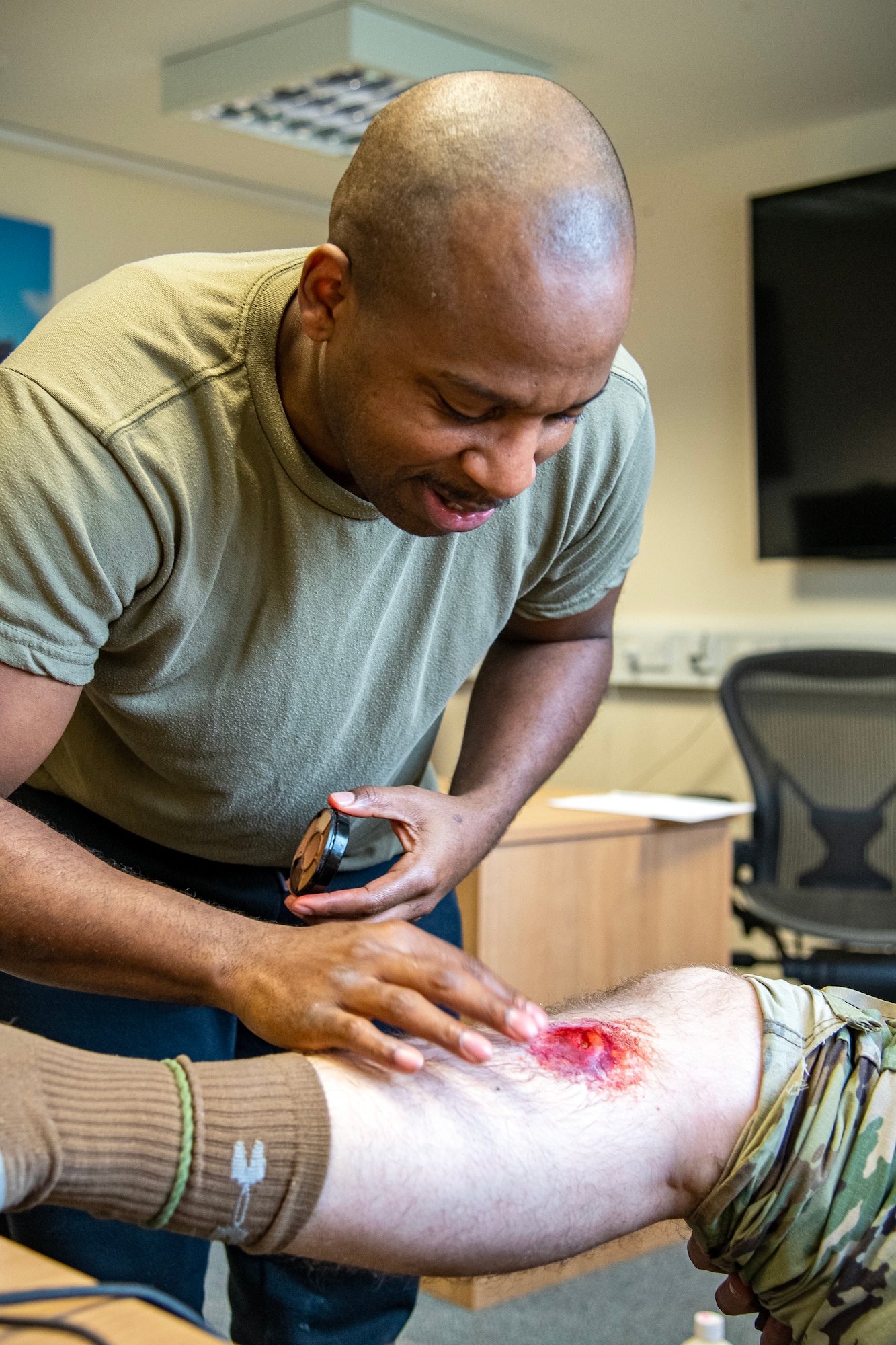 U.S. Air Force Tech Sgt. Dominique Lockley, 501st Combat Support Wing executive assistant to the Command Chief, applies moulage to a simulated victim at RAF Alconbury, England, March 16, 2023. The application was part of an exercise which tested the 501st CSW on overall readiness and ability to respond to an emergency situation. (U.S. Air Force photo by Staff Sgt. Eugene Oliver)