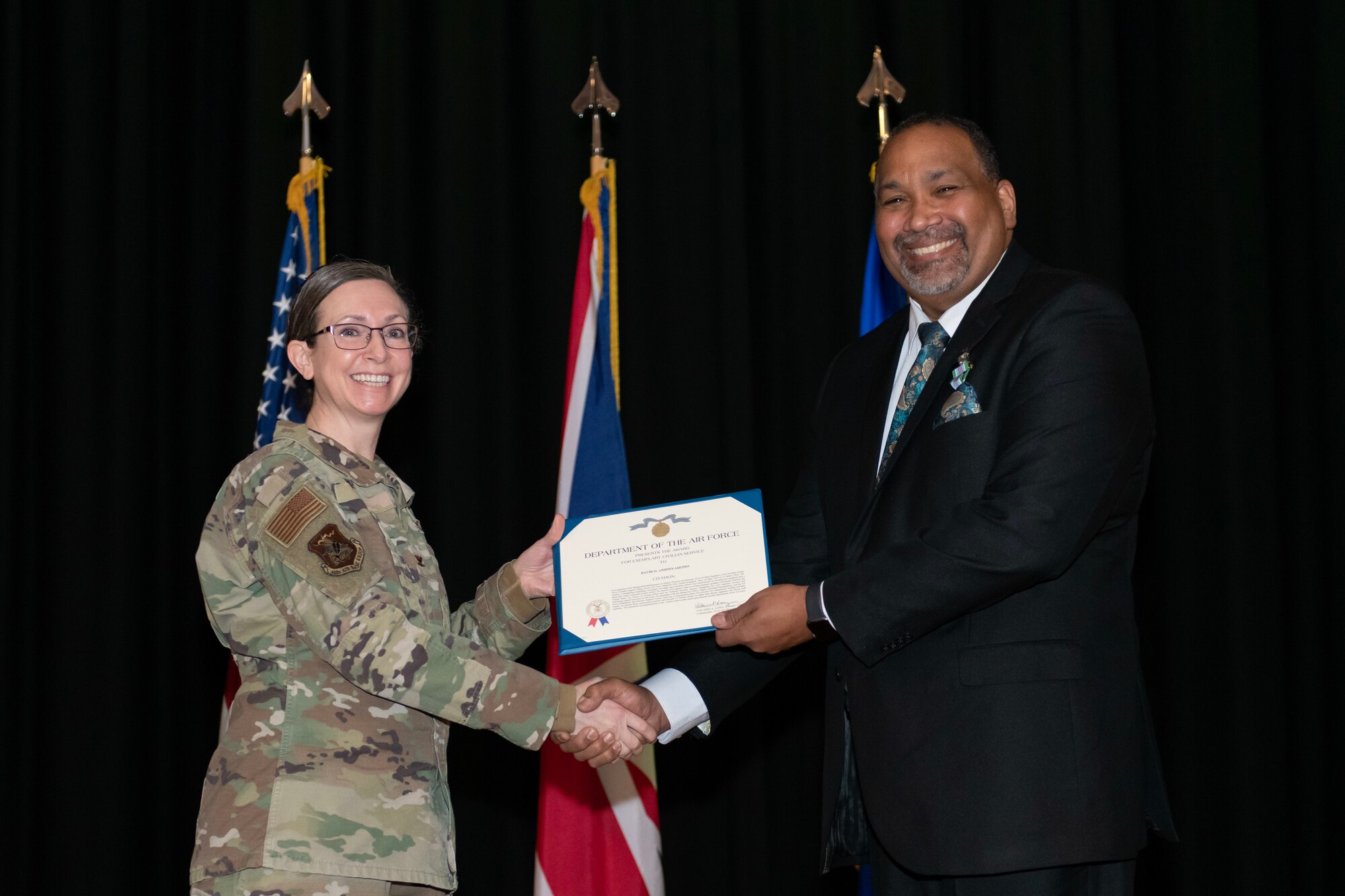 U.S. Air Force Col. Valarie Long, left, 423d Air Base Group commander, presents David Andino-Aquino, right, 421st Air Base Squadron director, the award of exemplary civilian service during a 421st ABS Relinquishment of Responsibility ceremony at RAF Alconbury, England, March 17, 2023. Andino-Aquino relinquished responsibility as 421st Air Base Squadron director. (U.S. Air Force photo by Staff Sgt. Jennifer Zima)