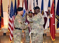 Col. Tony Nesbitt, right, outgoing commander of U.S. Army Medical Logistics Command, passes the unit colors to Maj. Gen. Robert Edmonson II, commanding general of U.S. Army Communications-Electronics Command, during a relinquishment of command ceremony March 10 at Fort Detrick, Maryland. Also pictured is AMLC Sgt. Maj. Akram Shaheed.