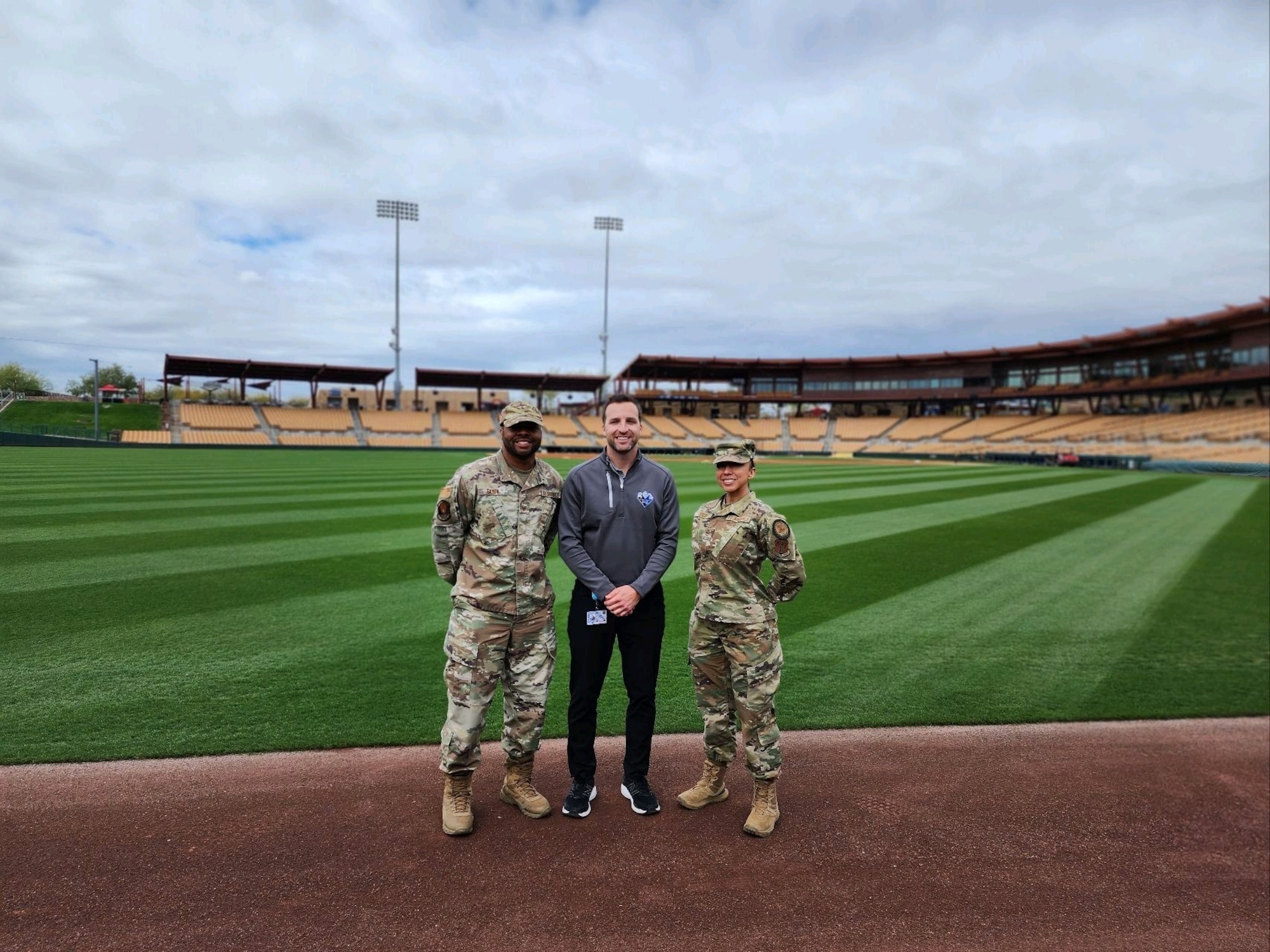 Dave Schermerhorn (middle) director, marketing, and corporate partnerships at Camelback Ranch–Glendale baseball complex, poses for a photo with Tech. Sgts. Anna Solis and Tech. Sgt. Glen Eason, production recruiters with the Arizona Air National Guard, in front of the Air National Guard outfield banner at Camelback Ranch–Glendale baseball complex in Phoenix, AZ. March 1, 2023.