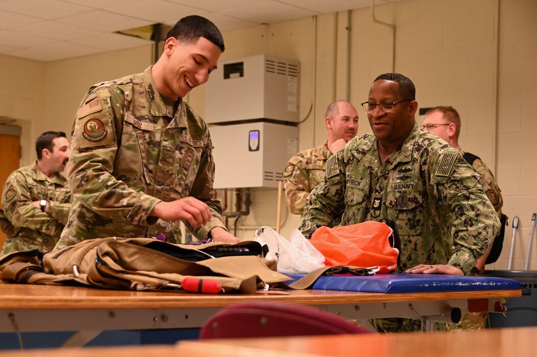U.S. Air Force Airman Jahaziel Ruiz, 97th Operations Support Squadron aircrew flight equipment apprentice, demonstrates how to pack a parachute to U.S. Navy Fleet Master Chief Donald O. Myrick, U.S. Transportation Command senior enlisted leader, at Altus Air Force Base, Oklahoma, March 15, 2023. The aircrew flight equipment office is responsible for testing and maintaining safety equipment as well as providing helmets and harnesses for aircrew. (U.S. Air Force photo by Senior Airman Kayla Christenson)