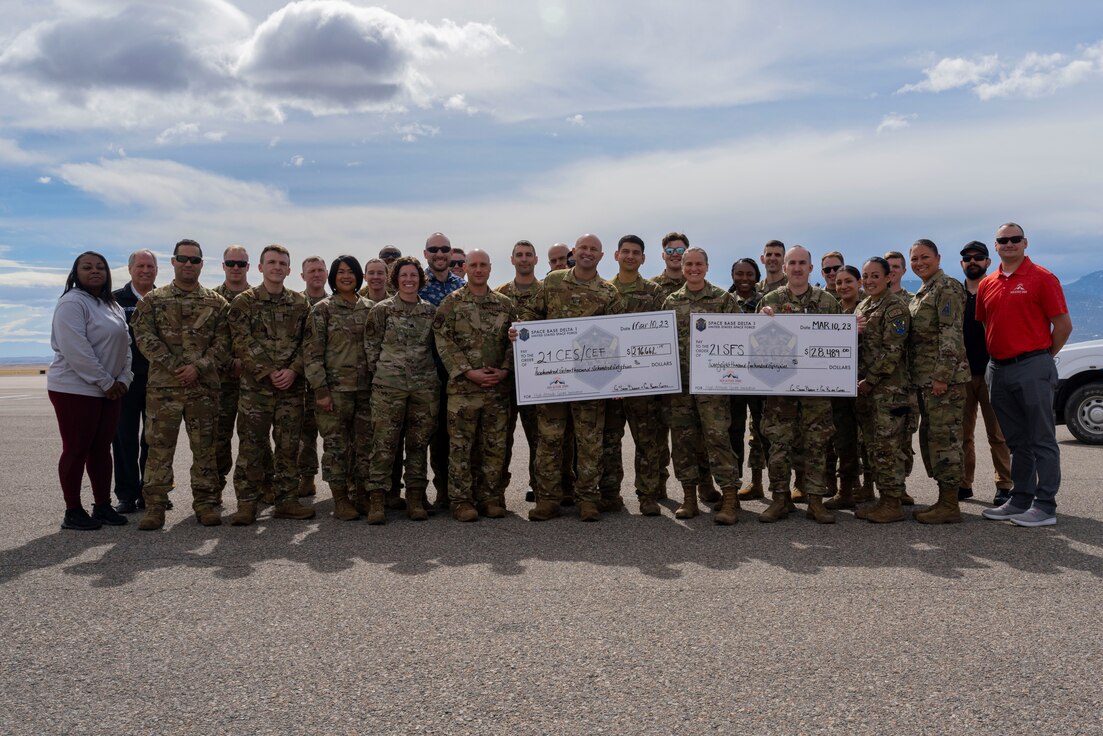 The High Altitude Spark team present checks for over $250,000 to representatives from the Peterson SFB Fire Department as well as the 21st Security Forces Squadron at Peterson SFB.