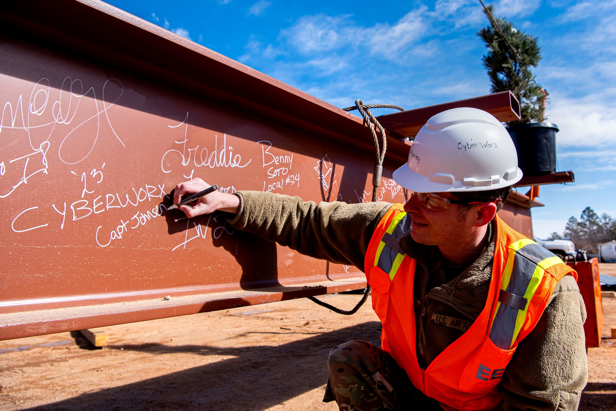 Capt Nathan Johnsen signs a steel beam during a topping off ceremony at the Air Force Academy, Colorado, February 14, 2023.