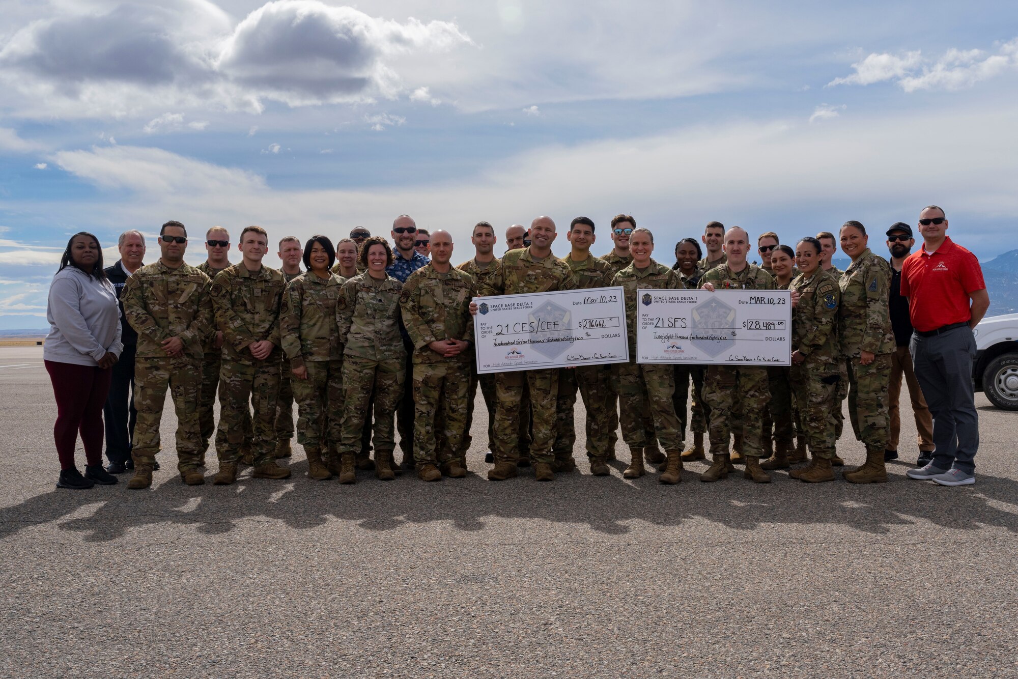 The High Altitude Spark team present checks for over $250,000 to representatives from the Peterson SFB Fire Department as well as the 21st Security Forces Squadron at Peterson SFB.
