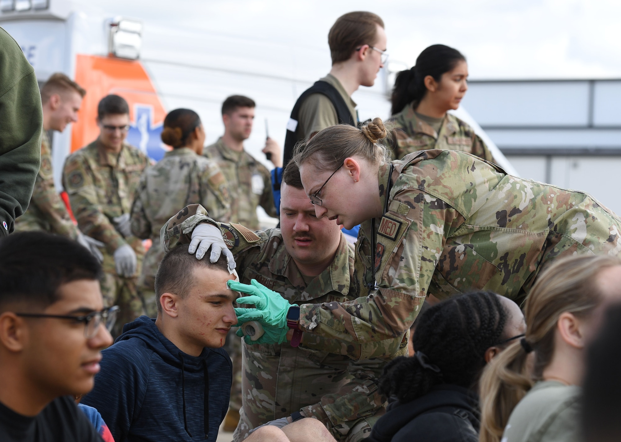 U.S. Air Force Staff Sgt. Tiffani Taylor, 81st Operational Medical Readiness Squadron medical technician and Senior Airman Austyn Ratliff, 81st OMRS medical technician, apply a bandage to Airman 1st Class Caleb Rouse, 334th Training Squadron student, who portrays an injured person during the aircraft mishap exercise at Keesler Air Force Base, Mississippi, March 16, 2023.