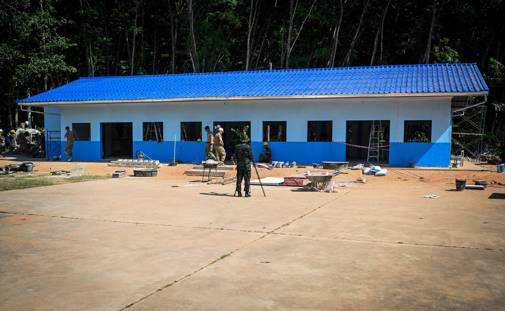 Engineers stand in front of a school house under construction