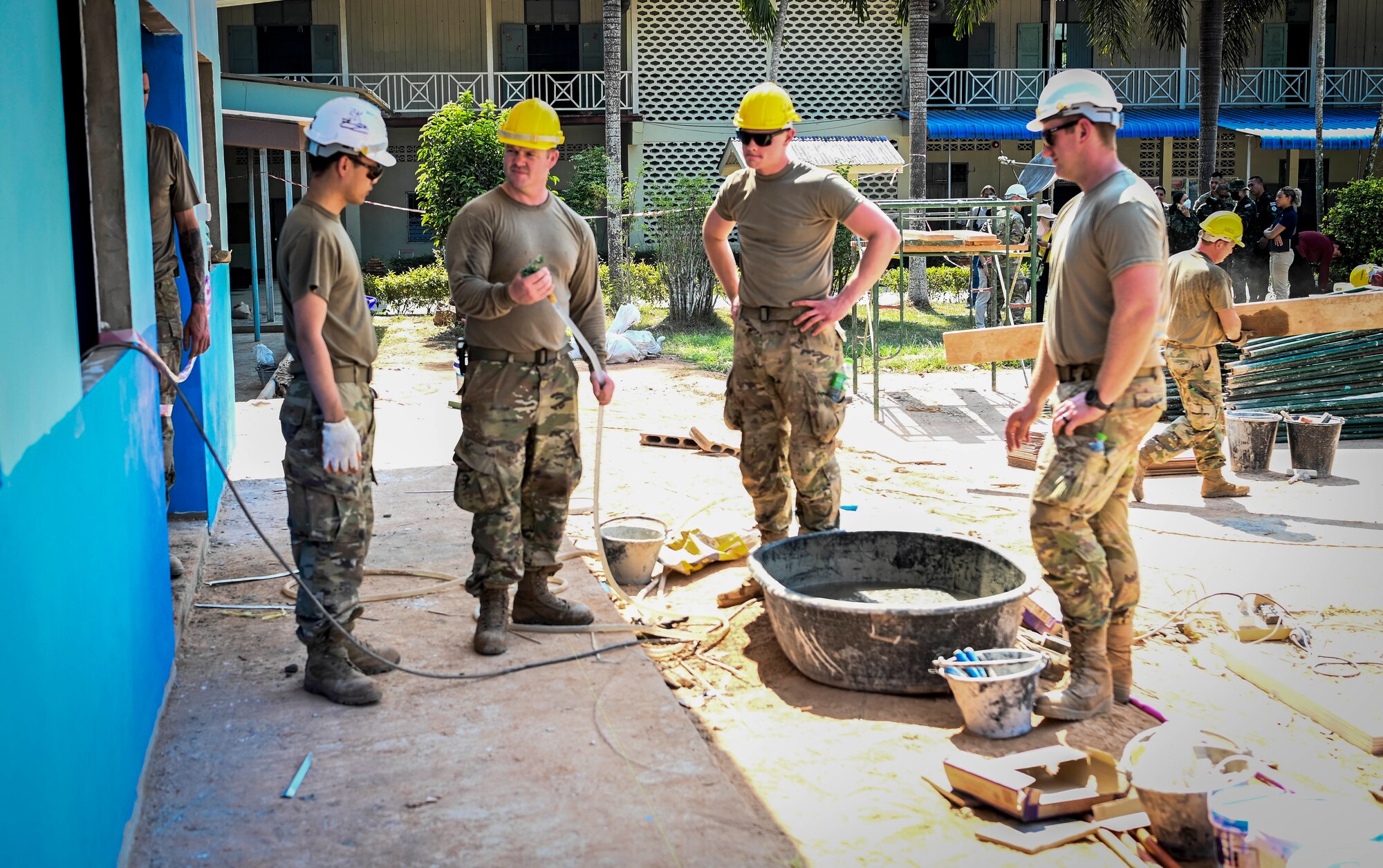 Four military engineers discuss next steps at a school house construction site