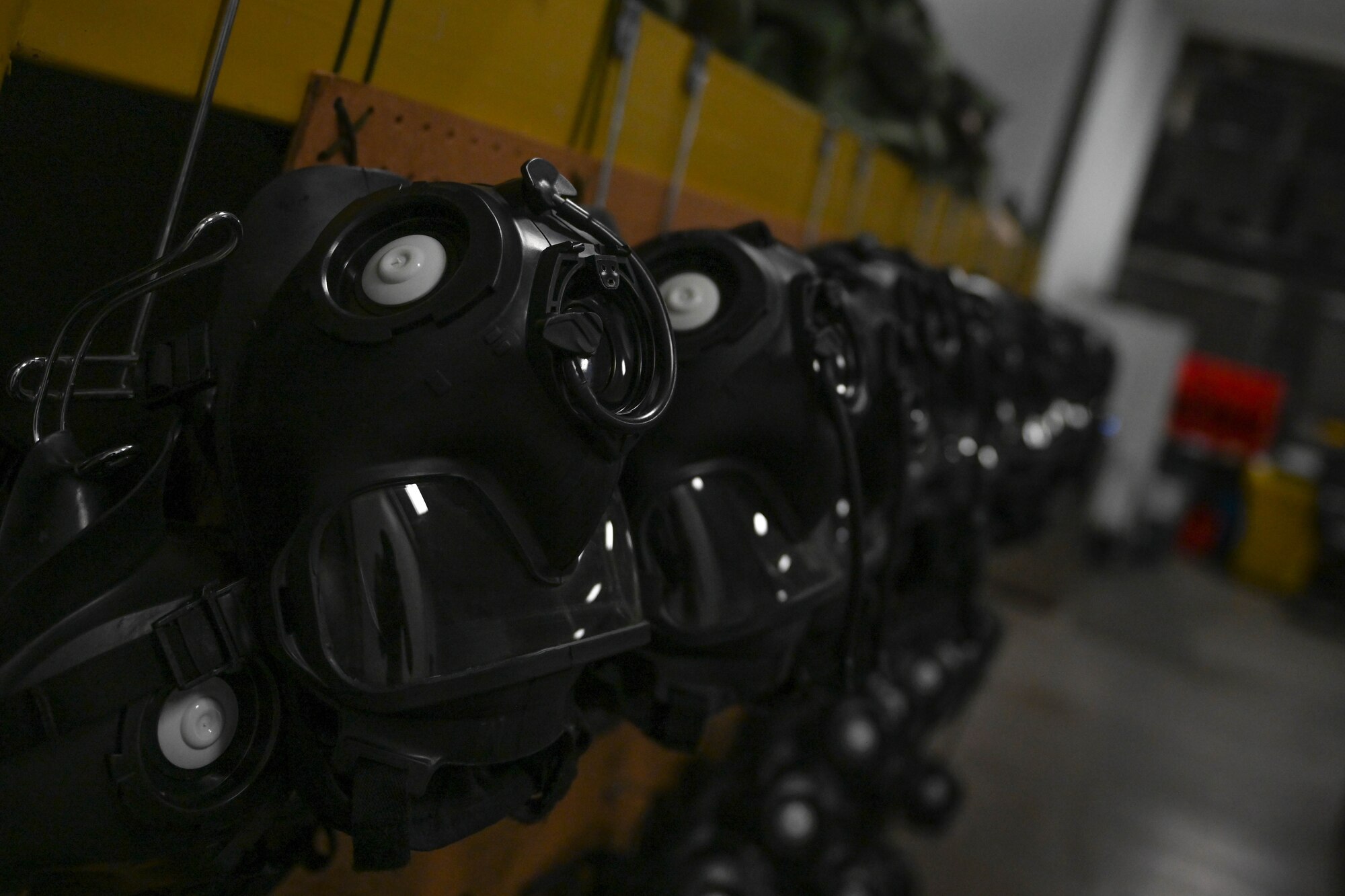 A row of gas masks hang on hooks.