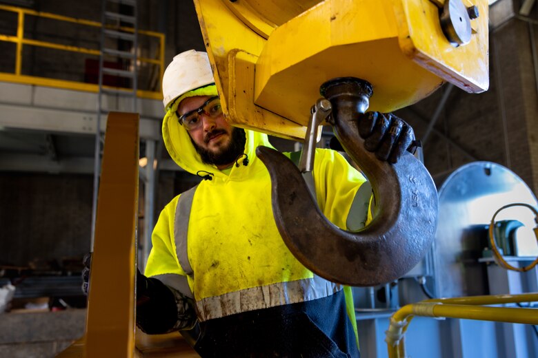 Parker Mathis, a contractor with BCI Construction USA, hooks the lifting beam to the overhead crane to install a new gate hoist in the Crooked Creek Dam control tower in Ford City, Pennsylvania, Feb. 14, 2023. BCI Construction installed four new hoists – each weighing 38,000 pounds apiece and control the dam’s gates – at Crooked Creek Lake to modernize the facility’s machinery and improve usage. The new hoists make the machinery safer and more efficient to use, with digital displays that are more accurate and easier to read. The original hoists were in operation since the dam was built in 1938. (U.S. Army Corps of Engineers photo by Andrew Byrne)