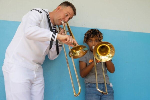 U.S. Navy Sailor MU2 Luke Reed, assigned to U.S. Naval Forces Europe and Africa, plays his instrument with Luis Martins, a fifth grader at the Escola Dona Tututa, in Sal Island, Cabo Verde, Mar. 18, 2023. Marines and Sailors supporting the African Maritime Forces Summit (AMFS), toured Sal Island and met with local students in a unique opportunity to learn about their culture prior to the opening day of the summit on March 20. Hosted by U.S. Naval Forces Europe and Africa (NAVEUR-NAVAF), the African Maritime Forces Summit (AMFS) is a strategic-level forum that brings African maritime and naval infantry leaders together with their international partners to address transnational maritime security challenges within African waters including the Atlantic Ocean, Indian Ocean, and Mediterranean Sea.
