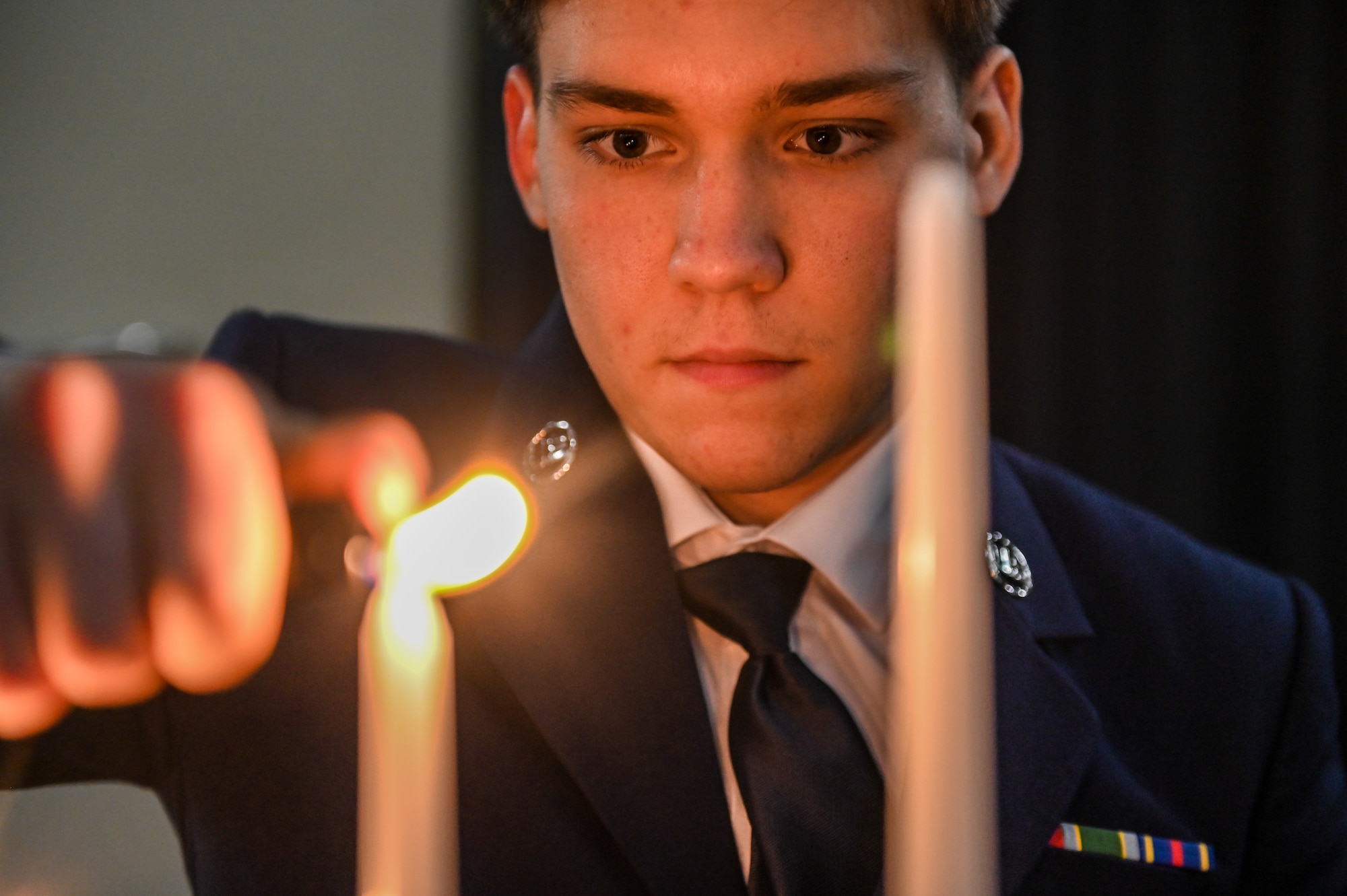 U.S. Air Force Airman 1st Class Cameron Barnes, 51st Maintenance Squadron aerospace propulsion apprentice, participates in a candle-lighting ceremony during a Chief Recognition Ceremony at Osan Air Base, Republic of Korea, March 17, 2023.