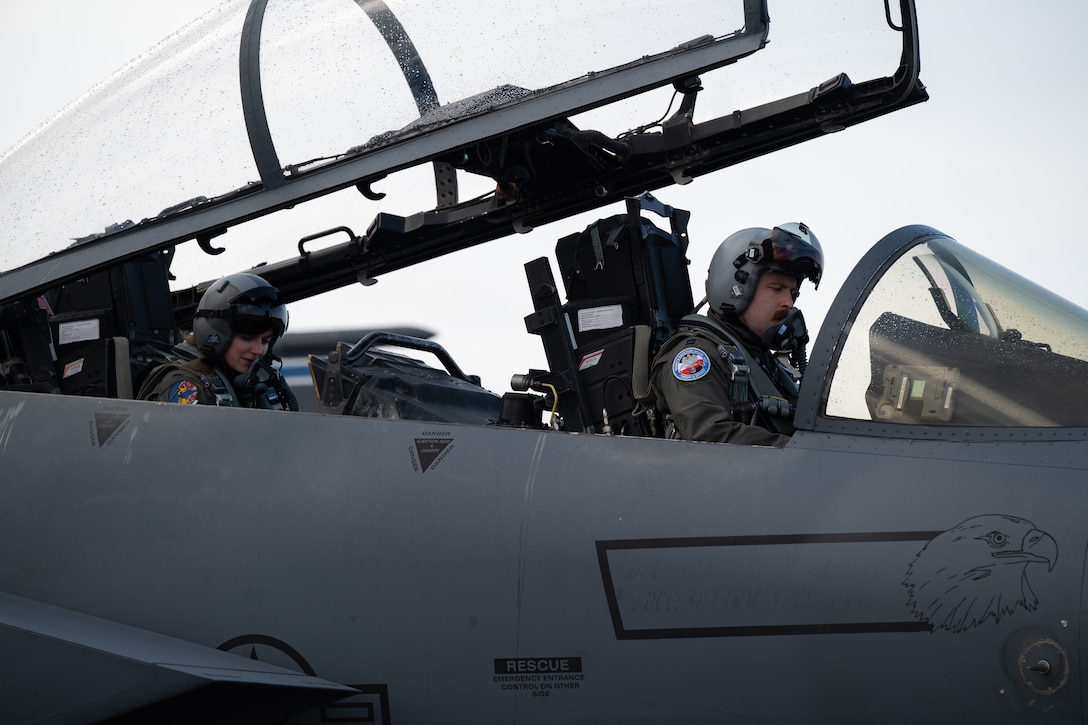 Two airmen sit in a cockpit of an aircraft.